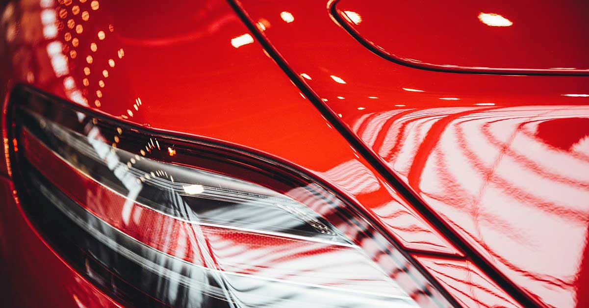 Nahaufnahme eines glänzenden roten Auto-Rücklichts mit unscharfen Lichtreflexen.